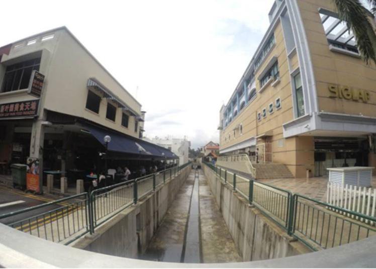 Upgraded canal-side drain with new safety railings adjacent to commercial shophouses