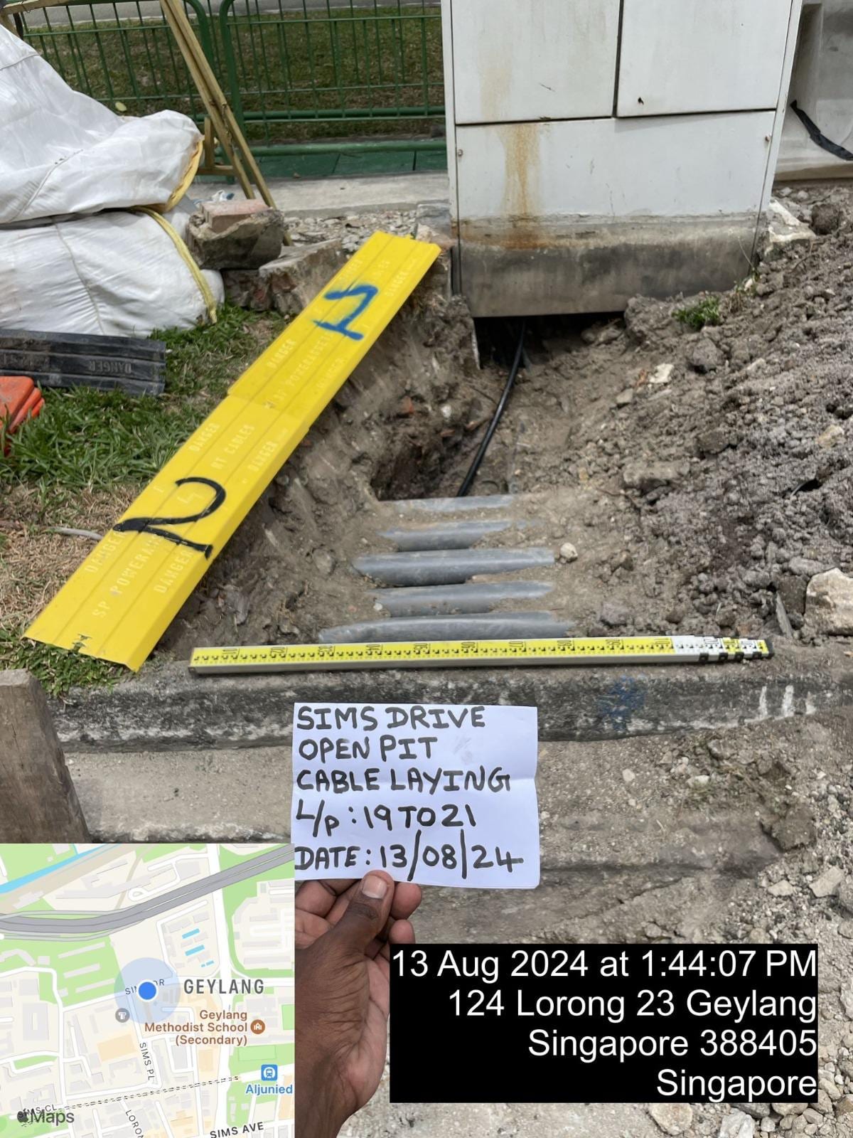 Open-pit cable laying works at Sims Drive — exposed utilities, trench shoring and Buildwick site signage